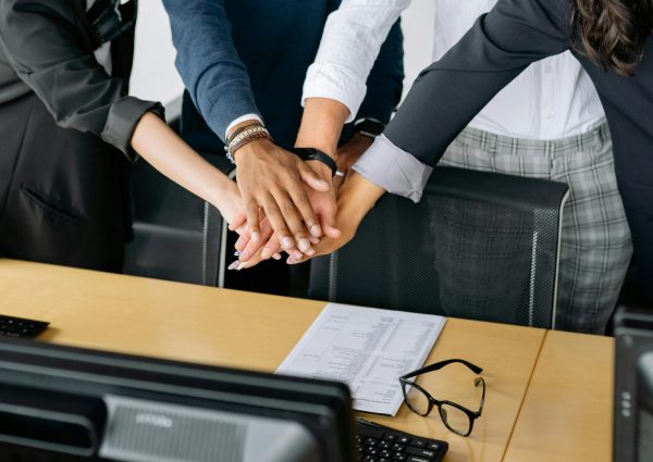 A close-up of a diverse business team stacking hands in unity, showcasing teamwork in an office setting.